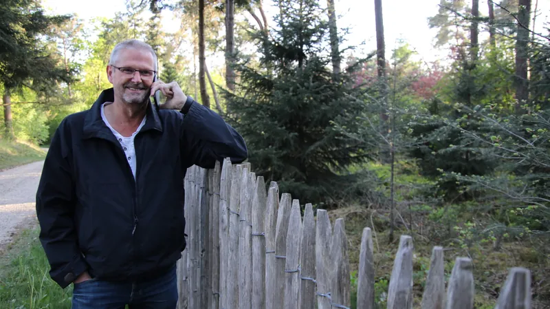 Joep van der Pol aan de telefoon bij een houten hek op de Veluwe