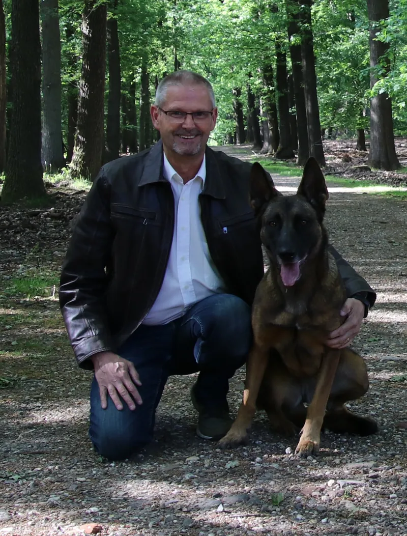 Joep van der Pol knielt op een bospad naast zijn herdershond
